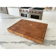 Wooden cutting board on a marble kitchen counter with stainless steel appliances in the background.