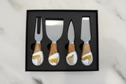 Set of four cheese knives with wooden handles in a black box on a light gray background